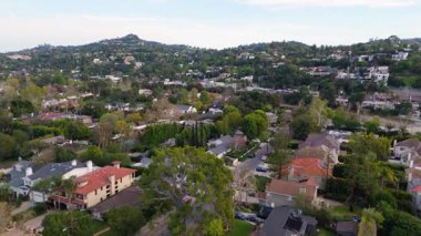 LOS ANGELES, CALIFORNIA, ABD, 20 Mart 2025. Studio City, Los Angeles 'ta bir yerleşim yerini gösteren editoryal hava görüntüleri. Kamera yeşil tepelerin üzerinde sorunsuzca uçuyor.