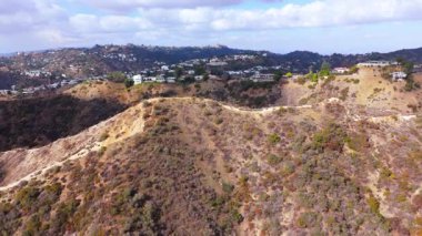 Hollywood Hills 'in çarpıcı hava görüntüleri lüks evler, dolambaçlı dağ yolları ve Los Angeles ufuk çizgisinin nefes kesici manzaraları. Manzaralı manzara, aralarındaki zıtlığı yakalar.