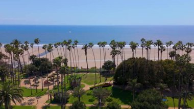 İnsansız hava aracı Palisades Parkı 'nın solundan sağa ve Kaliforniya' daki Santa Monica Sahili 'nin üstünden geçiyor. Kamera uzun palmiye ağaçlarını, yeşil park yollarını ve Pasifik Okyanusu boyunca uzanan geniş kıyı şeridini yakalar.