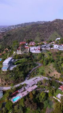 Los Angeles 'ta yemyeşil otlaklar, özel havuzlar ve kavisli yollarla lüks tepedeki konutların dikey hava görüntüleri. İnsansız hava aracı kamerası ileri geri hareket ederek modern mimariyi gözler önüne seriyor.