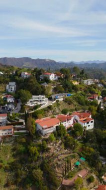 Los Angeles California Hollywood Hills 'teki lüks evlerin dikey drone görüntüleri. Panoramik görüntüler arasında ikonik Hollywood tabelası, lüks evler, yemyeşil ve dolambaçlı yollar yer alıyor. Kamera.
