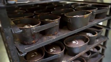 Endüstriyel bir fırında çikolata hamuruyla doldurulmuş metal kalıpların detaylı görüntüsü. Tepsilerin aşınmış dokusu ve işaretlenmiş hamur sahnenin arkasında otantik bir görünüm oluşturur.