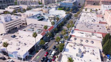 Beverly Hills, Los Angeles 'taki Rodeo Drive' ın ikonik alışveriş bölgesine bakan statik hava görüntüsü. Manzara, palmiye kaplı sokakları, tarihi mimariyi ve lüks butikleri yakalıyor.