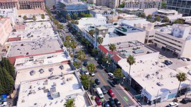 15 Nisan 2025 'te Beverly Hills, Kaliforniya' daki Rodeo Drive 'ın sabit yatay görüntüsü. Çerçevede lüks mağazalar, palmiye çizgili caddeler, park edilmiş arabalar ve ayrıntılı manzaralar yer alıyor.