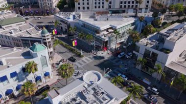 Beverly Hills, California 'daki Rodeo Drive' da canlı bir kavşağın statik hava görüntüsü, Burberry ve Dior gibi lüks butikler, palmiye çizgili kaldırımlar, yayalar, modern mimari