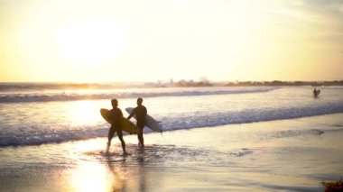 Gün batımında sörf tahtalarını ağır çekimde taşıyan iki sörfçü okyanusa girer. Altın ışığın gölgesinde, sığ sularda ilerleyip sörf yapmaya hazırlanıyorlar. Dalgalar uzaktaki bir yere çarpar.