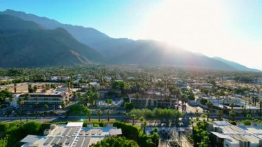 Dikey insansız hava aracı Palm Springs, Kaliforniya 'da gün doğumunun ilk ışıklarını yakalıyor. Yumuşak sabah ışınları çöl şehrini ve etrafındaki dağları aydınlatır. Huzurlu ve huzurlu bir ortam yaratır.