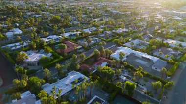 İnsansız hava aracı Palm Springs, Kaliforniya 'da bir banliyö mahallesinde aşağı doğru bir hareket yakalıyor. Sabahın erken saatlerinde güneş ışığı uzun gölgeler yaratır ve modern evlerin, palmiyelerin simetrisini ön plana çıkarır.