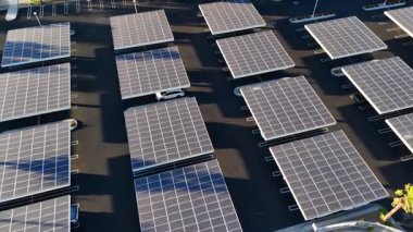Dinamik hava görüntüsü, Palm Springs 'teki bir otoparkın üstündeki güneş paneli kurulumlarına bakış açısını gösteriyor. Görüntüler şebeke benzeri oluşumu, modüler düzeni ve güçlü ışık gölgesini vurguluyor.