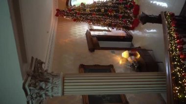 Noel Baba 'nın evi. Peri masallarındaki dayanılmaz bir Noel ağacı. Yılbaşı ağacı, eski bir kır evinin lüks içinde. Çelenklerle süslenmiş büyük bir merdiven. İrlanda. Dikey. Yavaş