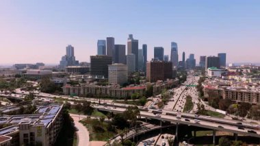Statik insansız hava aracı ön planda katmanlı otoyol kavşağı olan Los Angeles şehir merkezindeki ikonik ufuk çizgisini gösteriyor. Önde gelen gökdelenler ve şehir altyapısı çerçeveye hakim olarak,