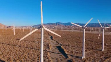 Palm Springs, California yakınlarındaki uçsuz bucaksız çölde bulunan modern bir rüzgar türbinine yakın bir hava aracı yaklaşımı. Detaylı çekim ön plandaki bıçakların yapısını ve hareketini ortaya koyuyor.