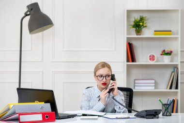 Ofiste çalışan sekreter. Gömlekli, iş yükü telefon görüşmesinde olan sevimli sarışın kız.
