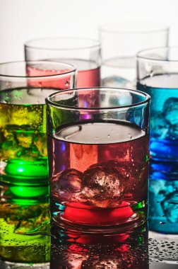 Renkli sıvılar ve buzla dolu canlı bardaklar.