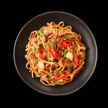 Taze sığır eti, taze sebze ve dilimlenmiş kırmızı biber içeren canlı bir tabak kızarmış şehriye, sade bir siyah kasede servis edilir. Sağlıklı bir yemek için mükemmel..