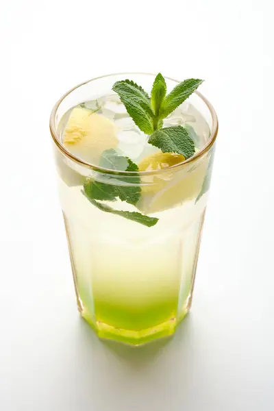 stock image A tall glass filled with crushed ice holds a refreshing mint-lime drink, garnished with fresh mint leaves and hints of lime, ideal for summer relaxation.