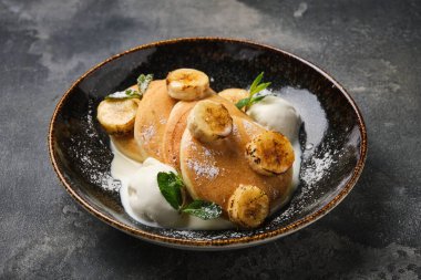 Üzerine muz dilimleri ve bir kepçe vanilyalı dondurma konmuş leziz krep servisi.