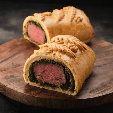 Elegant beef wellington with a perfect pink center and puff pastry crust, served on a rustic board clipart