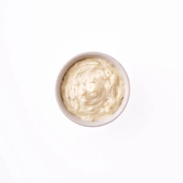 stock image A delightful creamy dip rests in a small bowl against a stark white backdrop, inviting taste buds to enjoy its rich texture at any social occasion.