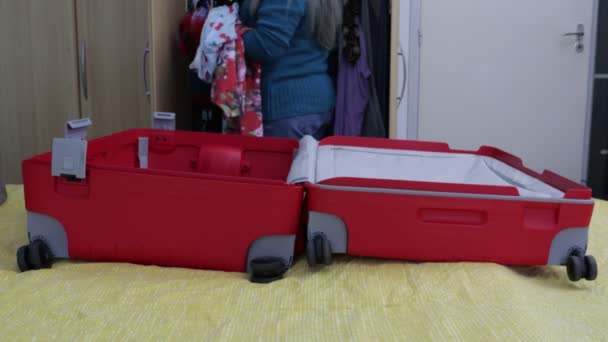 여성은 벽장에서 선택하고 침대에 지퍼를 가방에 여행을 준비하기 — 비디오
