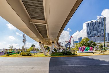 Zapopan, Jalisco Meksika. 1 Ocak 2023. Trafik, zürafa ve modern bina bulunmayan Acueducto Bulvarı üzerindeki araç köprüsünün alt perspektifi, mavi gökyüzüne karşı şehir manzarası, güneşli bir gün.