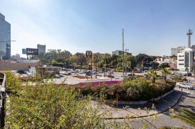 Guadalajara, Jalisco Meksika. 28 Aralık 2022. Bulanık arka planda caddeler, dükkanlar, sürücü arabaları, reklam panoları, binalar ve yeşil ağaçların şehri, güneşli bir gün.