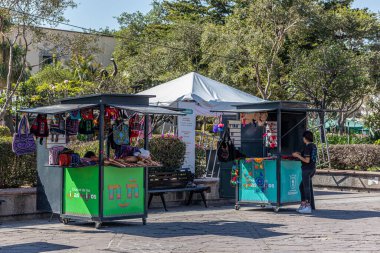 Zapopan, Jalisco Meksika. 7 Ocak 2023. Sokak tezgahları, Meryem Ana 'nın Bazilikası Plaza de las Americas' ın yanında el işi ve hediyelik eşya satıyor. Arka planda yeşil ağaçlar, güneşli bir gün. Şehir yaşamı manzarası