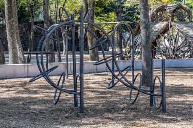 Halkalarla metal tırmanma oyunu eliptik biçimde açık bir tünel oluşturur, halka parkındaki açık çocuk eğlence alanı, bulanık arka planda ağaç gövdeleri, Meksika 'da güneşli bir gün.