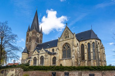 Güneyden mavi gökyüzüne karşı görülen etkileyici Roma Katolik Kilisesi, saati ve kocaman pencereleri olan çan kulesi, Hollanda 'da, Thorn, Midden-Limburg' da güneşli bir gün.