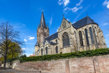 Güneyden mavi gökyüzüne bakan Katolik St. Michael Abbey Kilisesi 'nin düşük açılı perspektifi, saati ve kocaman pencereleri olan çan kulesi, Hollanda' daki Thorn, Midden-Limburg 'da güneşli bir gün.