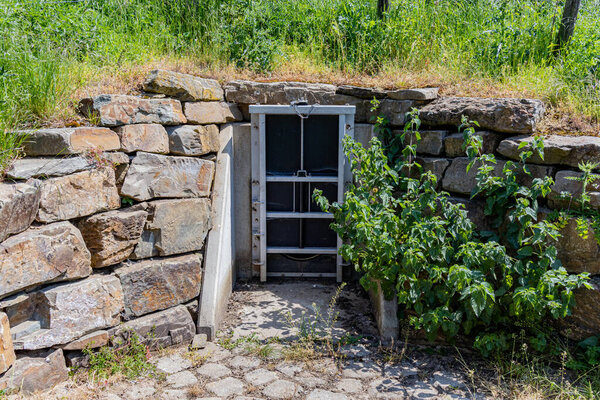 Drainage with water valve gate between stone walls and green grass, control system for high water levels due to climate change, Bemelerberg nature reserve in South Limburg, The Netherlands