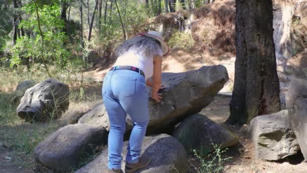 グアダラハラのロスコレモ公共公園で晴れた日を楽しんで 背景に座って景色 岩の丘を賞賛するためにいくつかの岩に登るシニア成人女性観光客 ジャリスコメキシコ — ストック動画