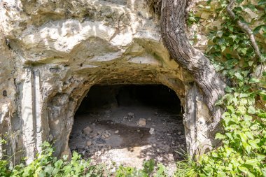 Taşlı kumlu bir mağaraya giriş, düzensiz doku ve çatlaklarla duvarlar, Belçika 'nın Sint-Pietersberg bölgesinde Thier de Lanaye doğa rezervi, Vise, Belçika' da güneşli bir yaz günü.