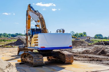 Kırsal yol inşaatındaki çalışma sahası, çalışma makineleri, endüstriyel arazi ve ağaçların arka planda mavi gökyüzü, Meers, Elsloo, Hollanda 'da güneşli bir gün