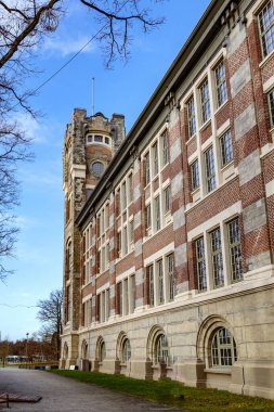 Mavi gökyüzü, çıplak ağaçlar, tuğla duvarlar ve kule, Thor Park - Hoge Kempen Ulusal Parkı, Genk, Belçika 'da güneşli bir sonbahar günü