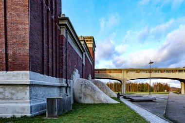Eski Waterschei madenindeki eski binanın yan görüntüsü, tuğla duvarlar ve binadan çıkan dev beton borular, Thor Park - Hoge Kempen Ulusal Parkı, Belçika Genk,