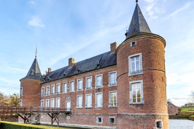 16. yüzyıldan Alden Biesen Kalesi, hendek, ahşap köprü, dairesel kule, tuğla duvarlar, pencereler ve çatı, dış avludan manzara, Bilzen, Limburg, Belçika 'da bulutlu bir gün.