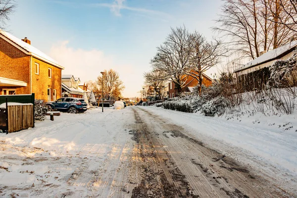 Winter cityscape, snow covered sidewalk and melting snow street with frozen dirty snow, rock salt to prevent cars from sliding or skidding, sunny day after heavy snowfall in South Limburg, Netherlands