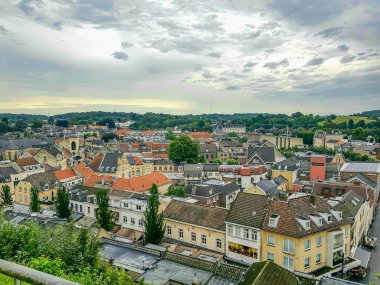 Terastan görünen Valkenburg şehri, şehir merkezinde çatıları olan binalar, arka planda sarı duvarlar, yapraklı ağaçlar, Güney Limburg, Hollanda 'da bulutlu bir gün.