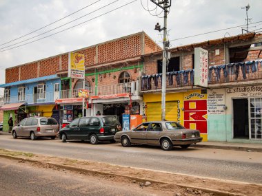 Zapopan, Jalisco Meksika. 15 Aralık 2009. Köyün kırsal kesimindeki ara sokaklarda dükkanları ve arabaları kaldırımın kenarına park edilmiş binalar bulutlu bulutlu bir günde bulutlarla kaplı.