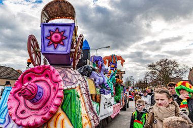 Beek, Güney Limburg, Hollanda. 3 Mart 2014. Renkli karnaval şamandıraları, at arabaları ve pembe Meksika şapkalarıyla kalabalığın arasında gezinen, eğlenen insanlar. Gri gökyüzü bulutlu bir gün