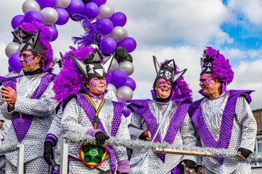 Beek, Güney Limburg, Hollanda. 3 Mart 2014. Gümüş ve mor giysiler giymiş bir grup insan, arka planda balonlar, kalabalığın arasında yüzen karnaval, mutluluğun ifadesi.