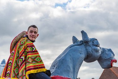 Beek, Güney Limburg, Hollanda. 3 Mart 2014. Meksika Charro 'su gibi giyinmiş genç bir adam bıyıklı, pançolu ve şapkalı gri eşeğin üzerinde, karnaval arabaları kalabalığın içinde, ciddi bir ifade.