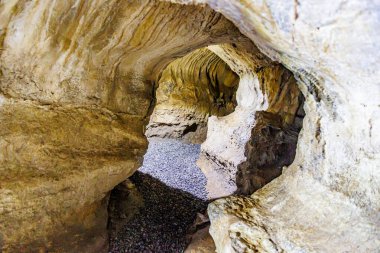 Underground tunnels inside cave in a rock formation at Logne Castle, irregular and grooved rock walls, illuminated with light lamps, summer day in Ferrieres, Belgium clipart