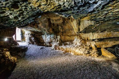 Logne Kalesi 'ndeki yeraltı mağarasının içinde güneş ışığıyla aydınlanan kapı ve lambalar, kayalık duvarlar düzensiz ve yivli Belçika' nın Ferrieres şehrinde yaz günü