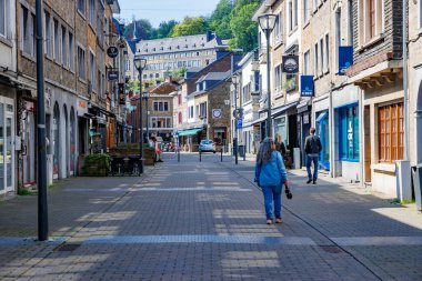 La Roche-en-Ardenne, Belçika. 4 Haziran 2024. Şehir hayatı manzarası, şehir merkezindeki ticari binalar arasındaki kaldırım taşı caddesi, çok az insan yürüyor, güneşli bir yaz günü.