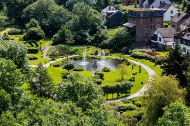 La Roche-en-Ardenne köyünün kentsel manzarası, çeşme, yaya yolları, yeşil yapraklı ağaçlarla çevrili evler, Wallonia bölgesinde güneşli bir yaz günü, Belçika
