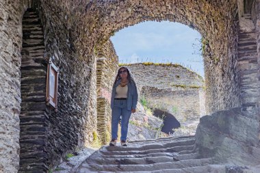 La Roche-en-Ardenne 'in harabelerinden geçen merdivenler. Tepesinde yaşlı bir turist duruyor. Zaman geçtikçe aşınan taş duvarlar, arka planda güneş ışığı, Belçika' da güneşli bir gün.