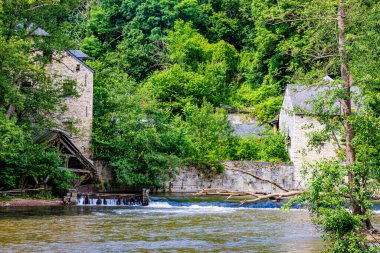 Lesse Nehri 'ndeki sızıntı, arka planda yeşil yapraklı ağaçlarla kaplı tepeli eski bir binanın taş duvarları Namur, Wallonia, Belçika' da güneşli bir yaz günü.