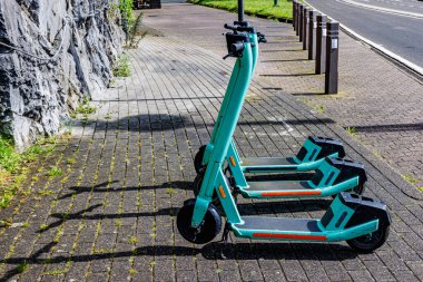 Üç yeşil elektrikli scooterı olan kaldırım kaldırımları. Profil manzaralı. Dinant kasabasının hemen yanında. Namur, Wallonia, Belçika 'da güneşli bir yaz günü.